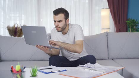 Young-man-looking-focused-on-laptop-at-home.